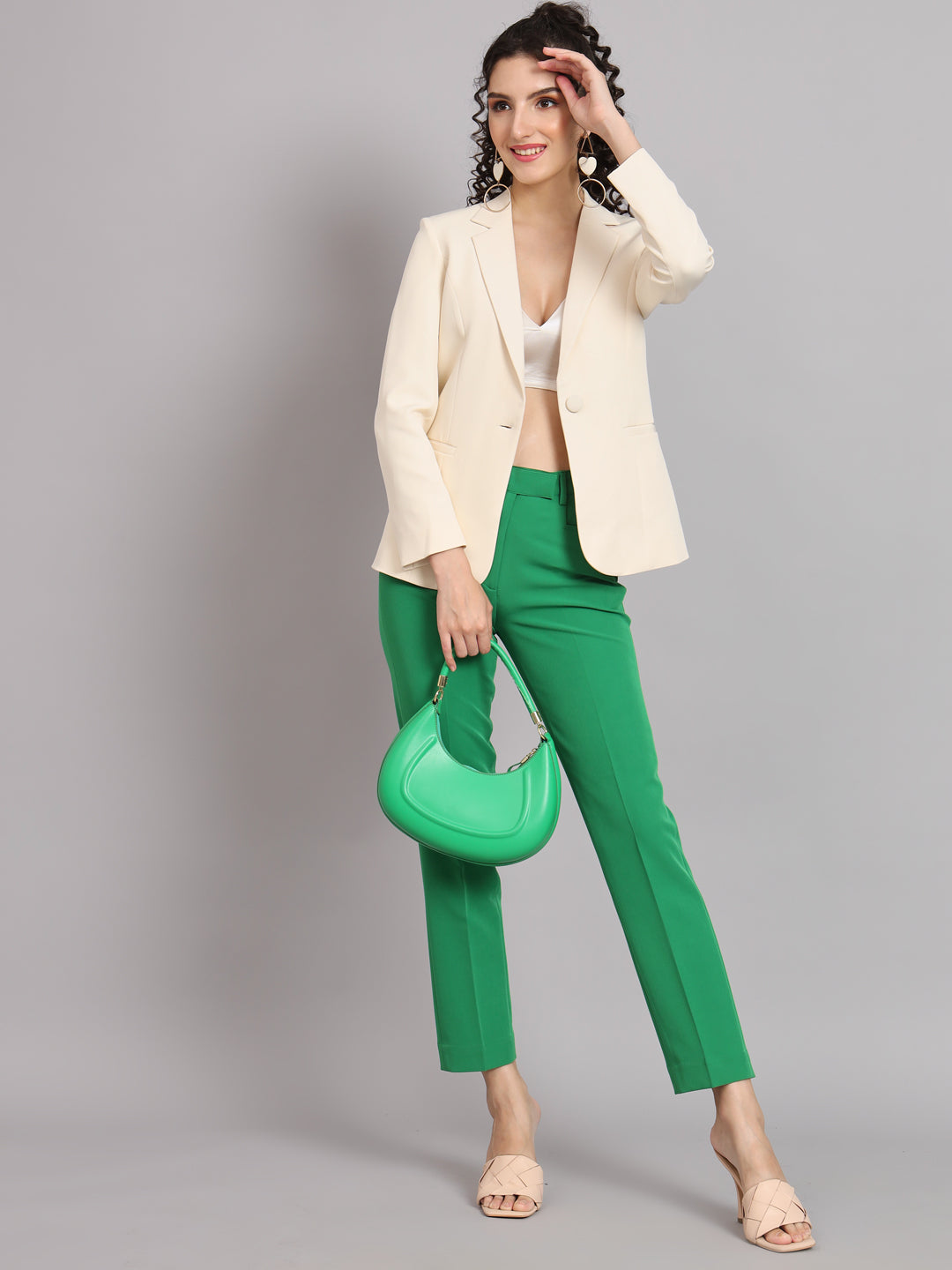 Notched collar off white blazer styled with green pants and accessories.